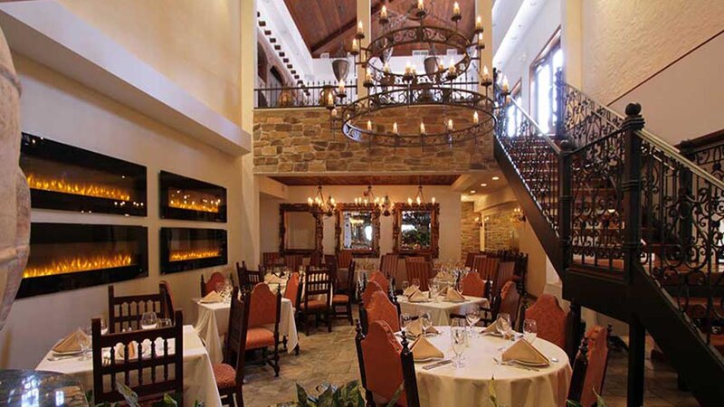 First floor atrium dining room displaying fire places, mirros, chandeiler and stairway ascending to the second floor