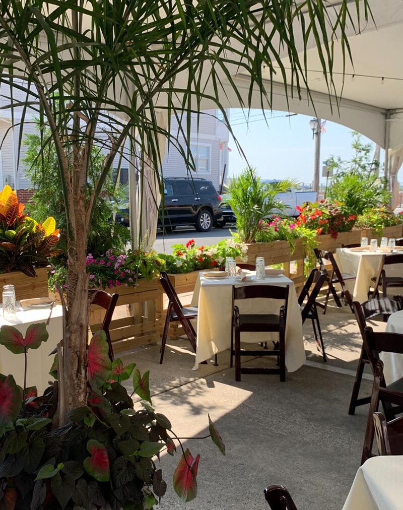 Outsiding dining area with view of many flowers and palm trees